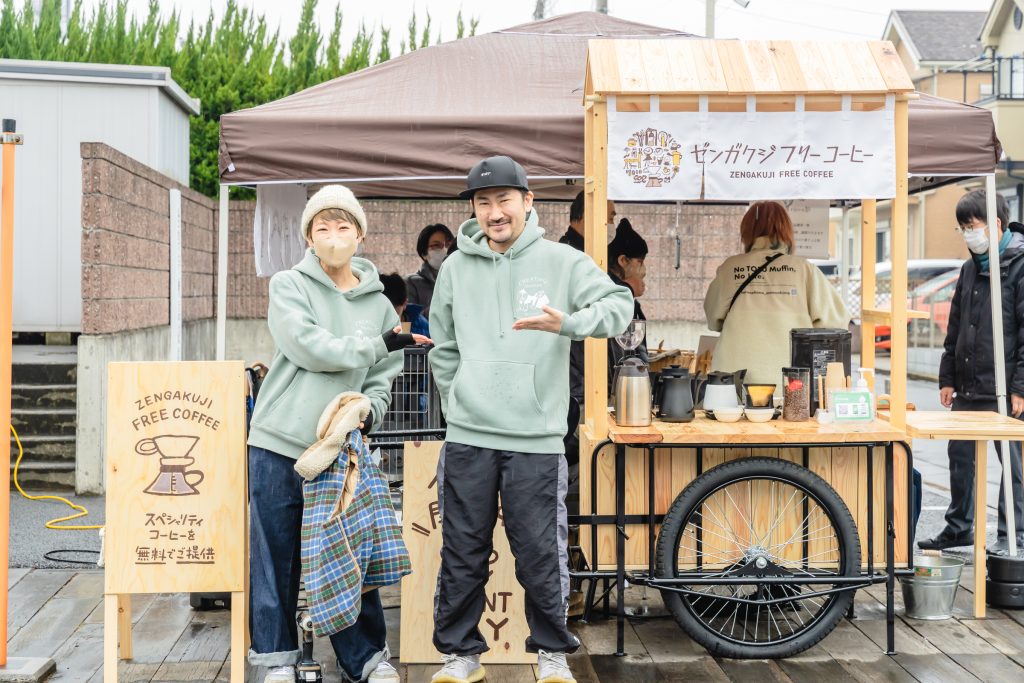 YORIKOさん（左）と大島（右）「想造楽工」が制作した「ゼンガクジ フリー コーヒー」のビジュアル・屋台と共に